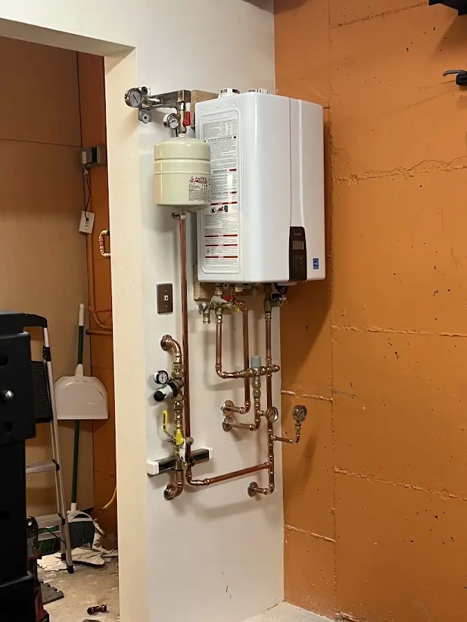 Plumbing technician inspecting water heater connections in Comstock